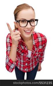 happiness and gesture concept - smiling teenager in eyeglasses with finger up