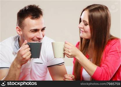 Happiness and healthy relationship concept. Attractive couple drinking tea or coffee together, man and woman holding mugs with hot beverage