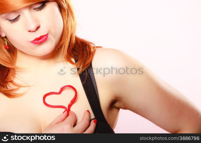 Happiness and love concept. Happy redhair woman smiling girl holding valentine red heart on chest. Valentines day.