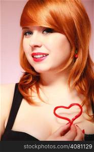 Happiness and love concept. Happy redhair woman smiling girl holding valentine red heart on chest. Valentines day.
