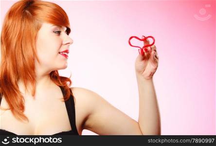 Happiness and love concept. Happy redhair woman smiling girl holding valentine red heart on pink. Valentines day.
