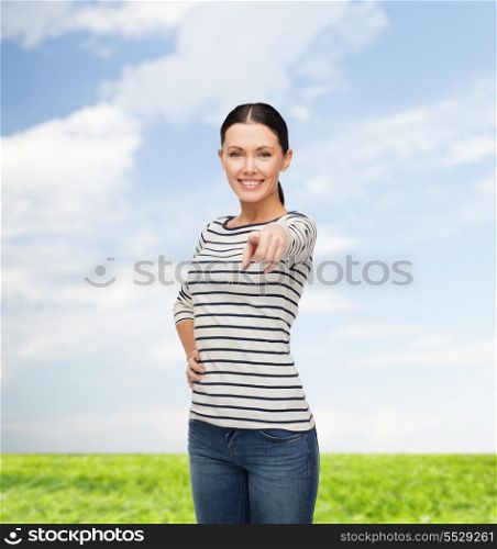 happiness and people concept - smiling girl in casual clothes pointing at you