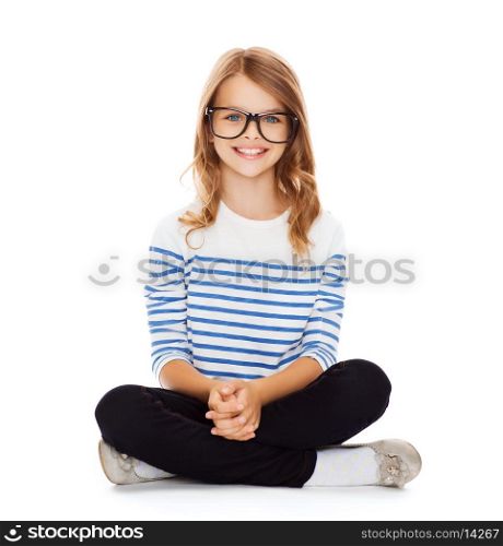 happiness and people concept - smiling girl in eyeglasses sitting on floor