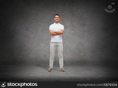 happiness and people concept - smiling man in white t-shirt with crossed arms over concrete background