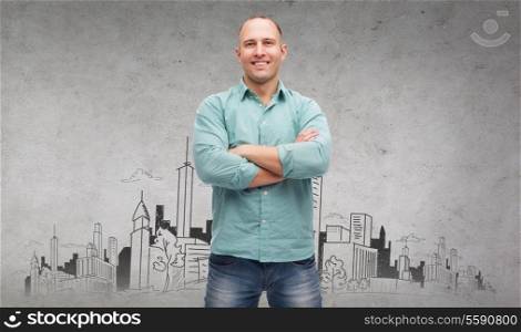 happiness and people concept - smiling man with crossed arms and city drawing in the back