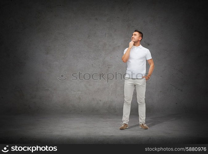 happiness and people concept - smiling man with hands in pockets looking up and thinking over concrete background