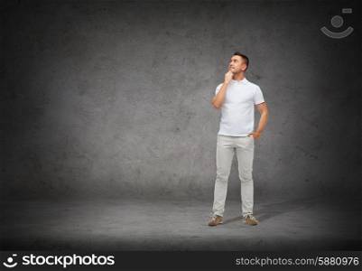 happiness and people concept - smiling man with hands in pockets looking up and thinking over concrete background