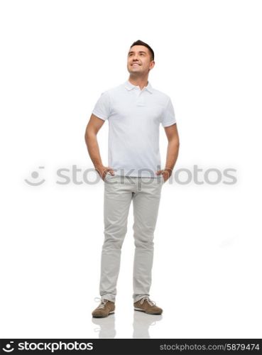 happiness and people concept - smiling man with hands in pockets looking up