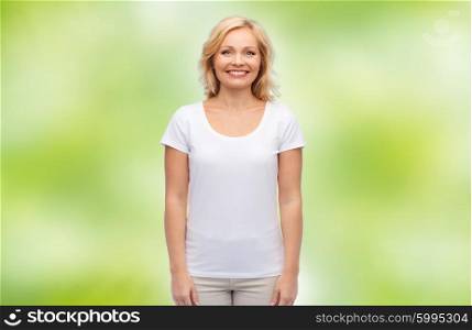 happiness and people concept - smiling middle aged woman in blank white t-shirt over green natural background. smiling middle aged woman in blank white t-shirt