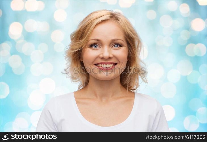 happiness and people concept - smiling woman in blank white t-shirt over blue holidays lights background. smiling woman in blank white t-shirt