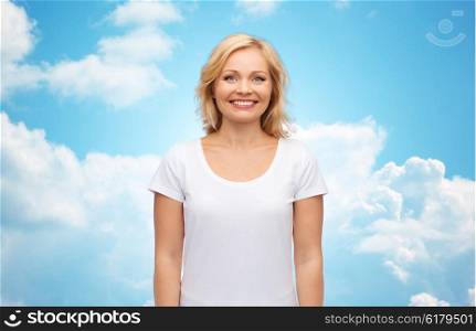 happiness and people concept - smiling woman in blank white t-shirt over blue sky and clouds background. smiling woman in blank white t-shirt