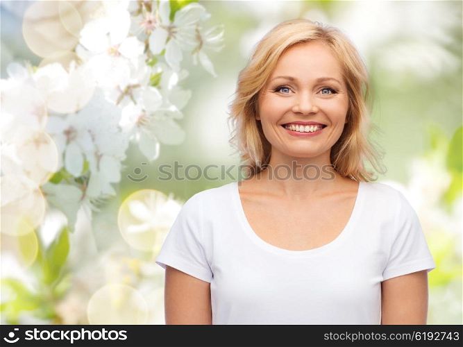 happiness and people concept - smiling woman in blank white t-shirt over natural spring cherry blossom background. smiling woman in blank white t-shirt
