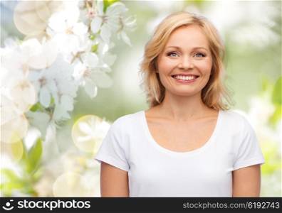 happiness and people concept - smiling woman in blank white t-shirt over natural spring cherry blossom background. smiling woman in blank white t-shirt