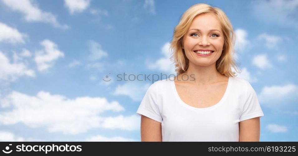 happiness and people concept - smiling woman in blank white t-shirt over blue sky and clouds background. smiling woman in blank white t-shirt