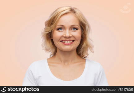 happiness and people concept - smiling woman in blank white t-shirt over beige background. smiling woman in blank white t-shirt