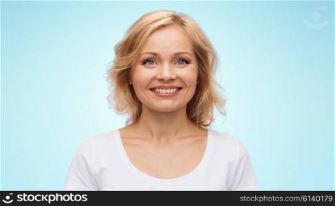 happiness and people concept - smiling woman in blank white t-shirt over blue background. smiling woman in blank white t-shirt