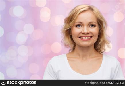 happiness and people concept - smiling woman in blank white t-shirt over pink lights background. smiling woman in blank white t-shirt