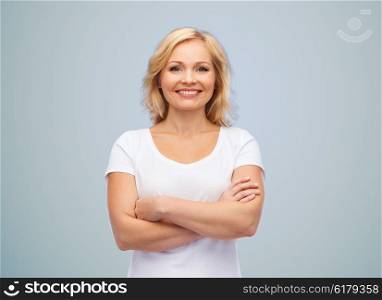 happiness and people concept - smiling woman in blank white t-shirt with crossed arms over gray background. smiling woman in blank white t-shirt