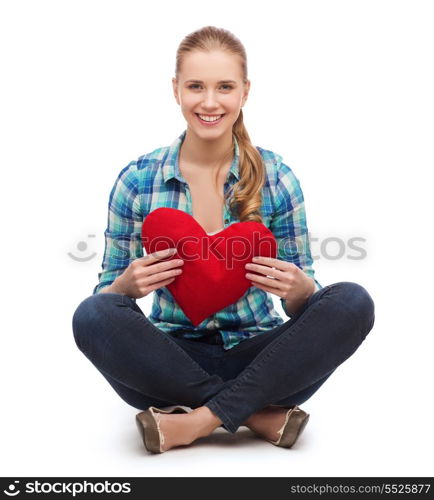 happiness and people concept - smiling young woman in casual clothes sitiing on floor and holding red heart