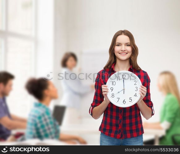 happiness and people concept - smiling young woman in casual clothes with wall clock showing 8 oclock