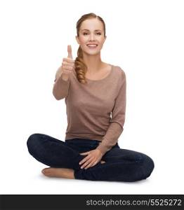 happiness and people concept - smiling young woman sitting on floor and showing thumbs up