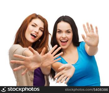 happiness and people concept - two smiling girls showing their palms