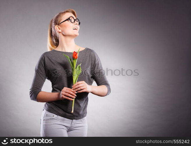 Happiness and satisfaction with life. Blonde woman wearing eyewear with single red green tulip. Happy joy girl feeling spring time holding beautiful flower.. Happy blonde woman with spring flower.