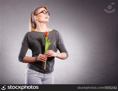Happiness and satisfaction with life. Blonde woman wearing eyewear with single red green tulip. Happy joy girl feeling spring time holding beautiful flower.. Happy blonde woman with spring flower.