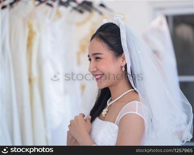 Happiness asian bride in white wedding dress with veil and beautiful pearl necklace.