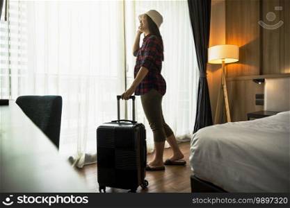 Happiness Asian traveler woman standing with baggage in bedroom of hotel or hostel when traveling on her holiday, luxury interior bedroom design, tourism and travel concept