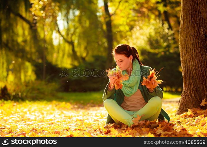Happiness carefree and nature. Young pretty woman relaxing in the autumn park holding orange leaves