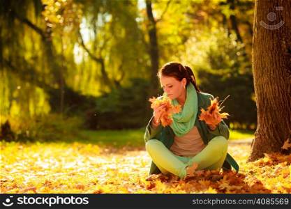 Happiness carefree and nature. Young pretty woman relaxing in the autumn park holding orange leaves