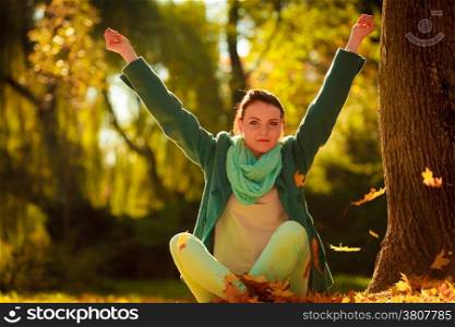 Happiness carefree. woman relaxing in autumn park throwing leaves up in the air with arms raised up. Beautiful girl in colorful forest foliage outdoor.