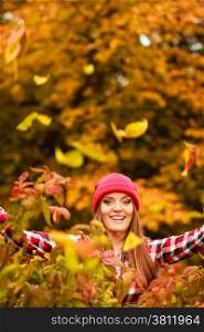 Happiness carefree. woman relaxing in autumn park throwing leaves up in the air with arms raised up. Beautiful girl in colorful forest foliage outdoor.