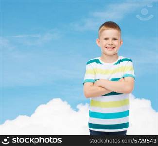 happiness, childhood and people concept - smiling little boy in casual clothes with crossed arms over blue sky background