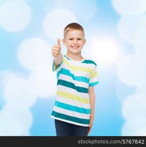 happiness, childhood and people concept - smiling little boy in casual clothes with showing thumbs up over blue background