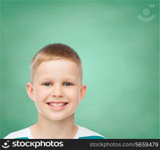 happiness, childhood and people concept - smiling little boy over green board background