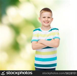 happiness, childhood, ecology and people concept - smiling little boy in casual clothes with crossed arms over green background