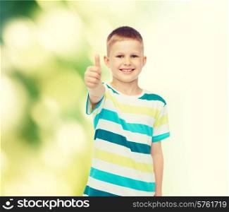 happiness, childhood, ecology and people concept - smiling little boy in casual clothes showing thumbs up over green background