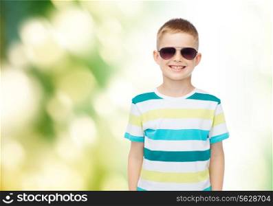 happiness, childhood, ecology and people concept - smiling little boy over green natural background