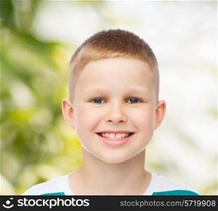 happiness, childhood, ecology and people concept - smiling little boy over green natural background
