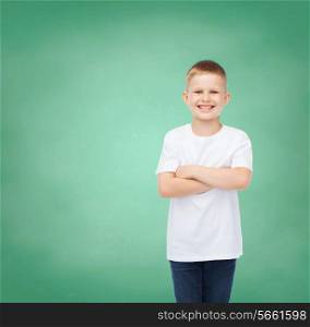 happiness, childhood, education, school and people concept - smiling little boy in white t-shirt over green board background