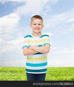happiness, childhood, environment and people concept - smiling little boy in casual clothes with crossed arms over natural background
