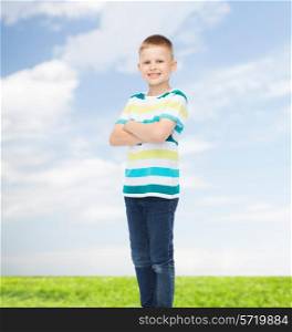 happiness, childhood, environment and people concept - smiling little boy in casual clothes with crossed arms over natural background