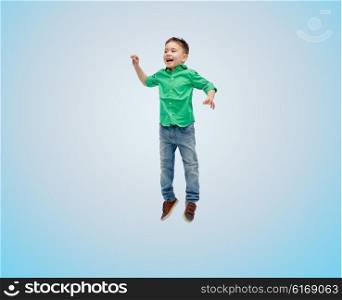 happiness, childhood, freedom, movement and people concept - happy little boy jumping in air over blue background