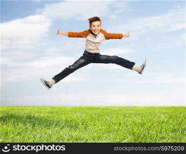 happiness, childhood, freedom, movement and people concept - happy smiling boy jumping in air over blue sky and grass background