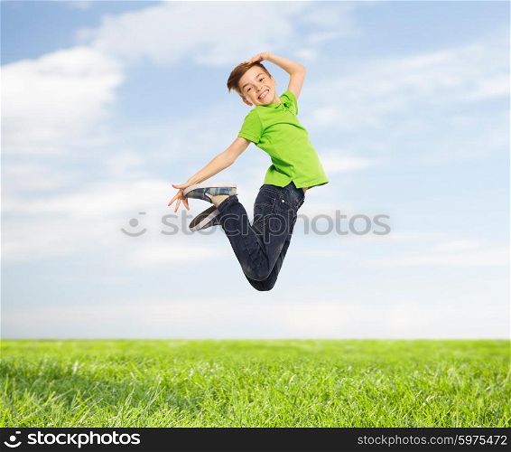 happiness, childhood, freedom, movement and people concept - smiling boy jumping in air over blue sky and grass background