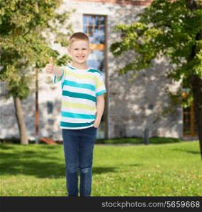 happiness, childhood, gesture, leisure and people concept - smiling little boy in casual clothes showing thumbs up over campus background