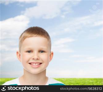 happiness, childhood, nature and people concept - smiling little boy over blue natural background