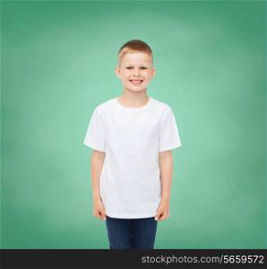 happiness, childhood, school education, advertisement and people concept - smiling little boy in white t-shirt over green board background